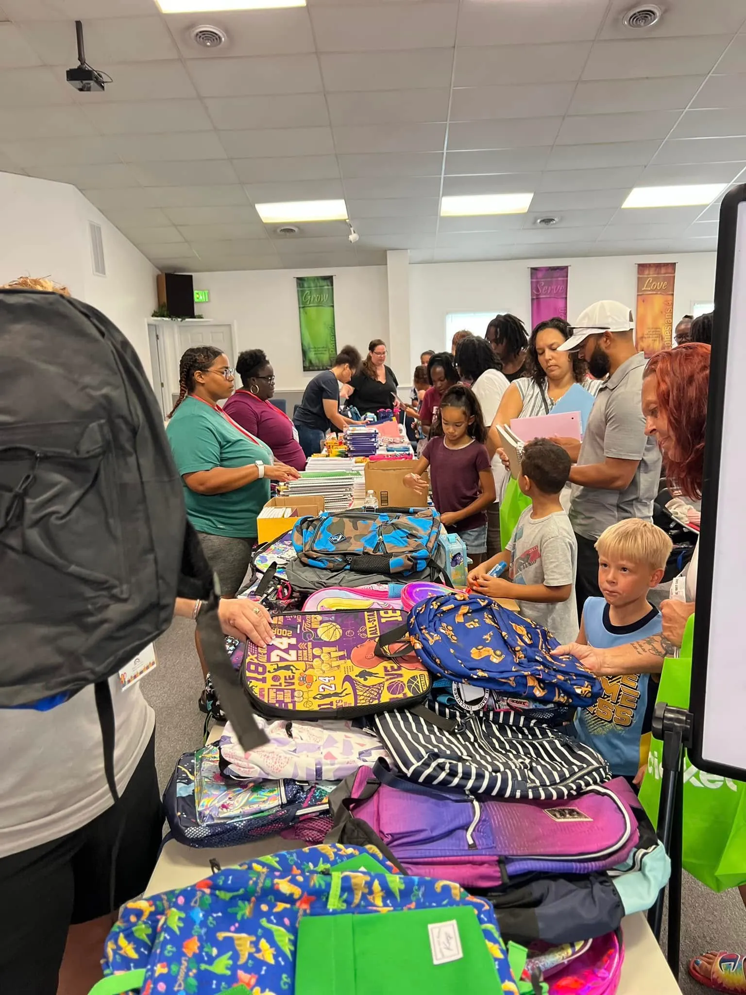 Children and families choosing backpacks and school supplies at a New Vision Ministries outreach event